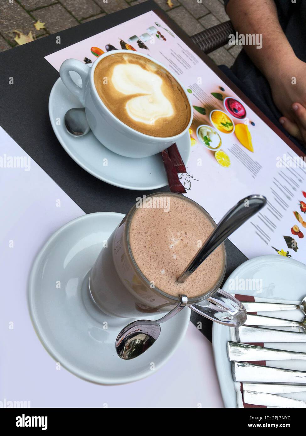 Eine Tasse Cappucino und ein Glas heiße Schokolade auf dem Tisch Stock Photo