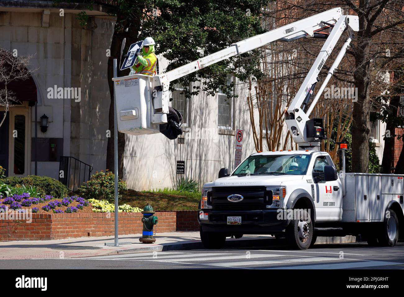 A worker in a Versalift bucket truck, aerial work platform, installs a one way street sign in Washington DC. Stock Photo