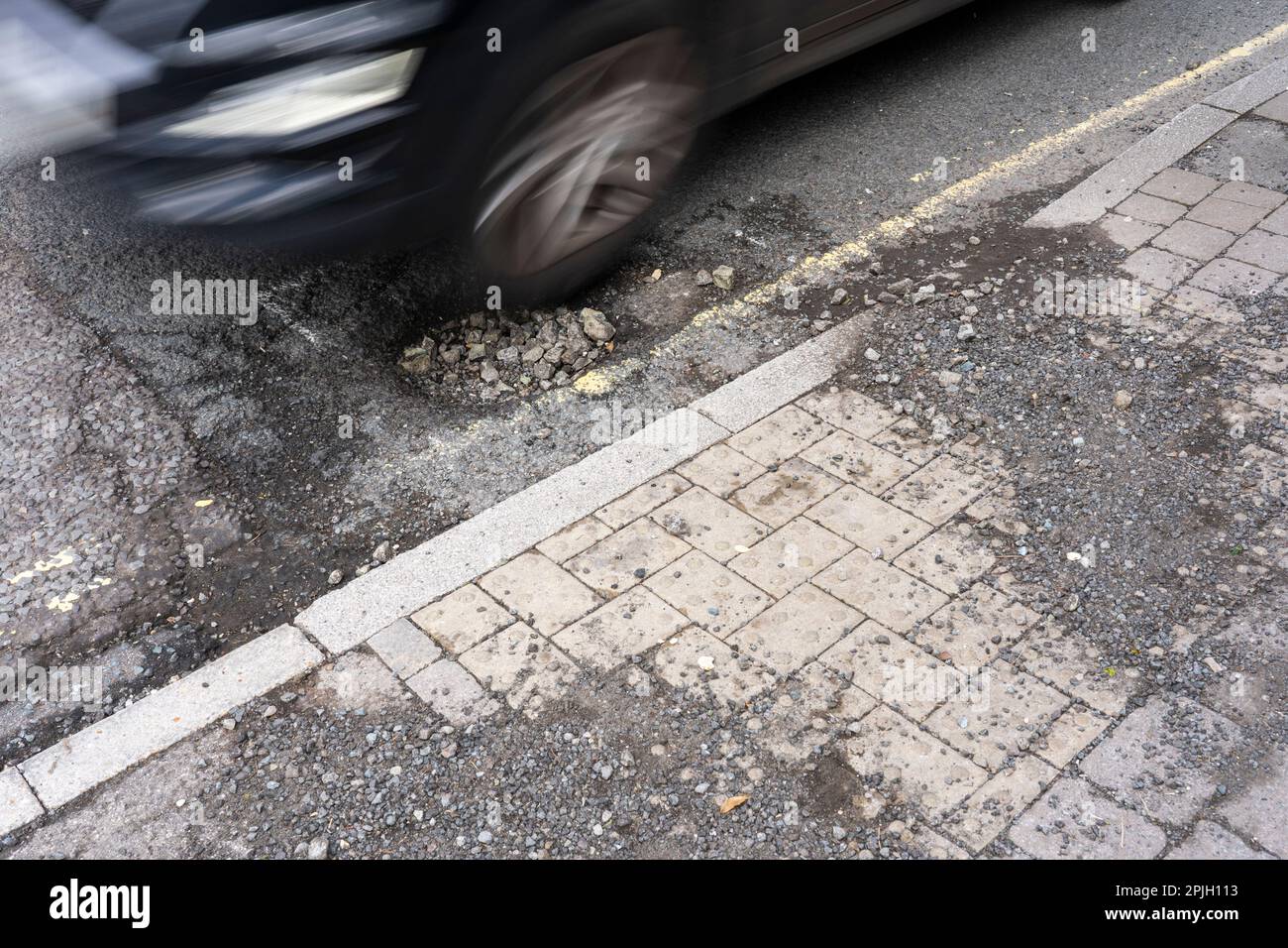Car driving through large pothole on Winchester Road, Basingstoke, UK