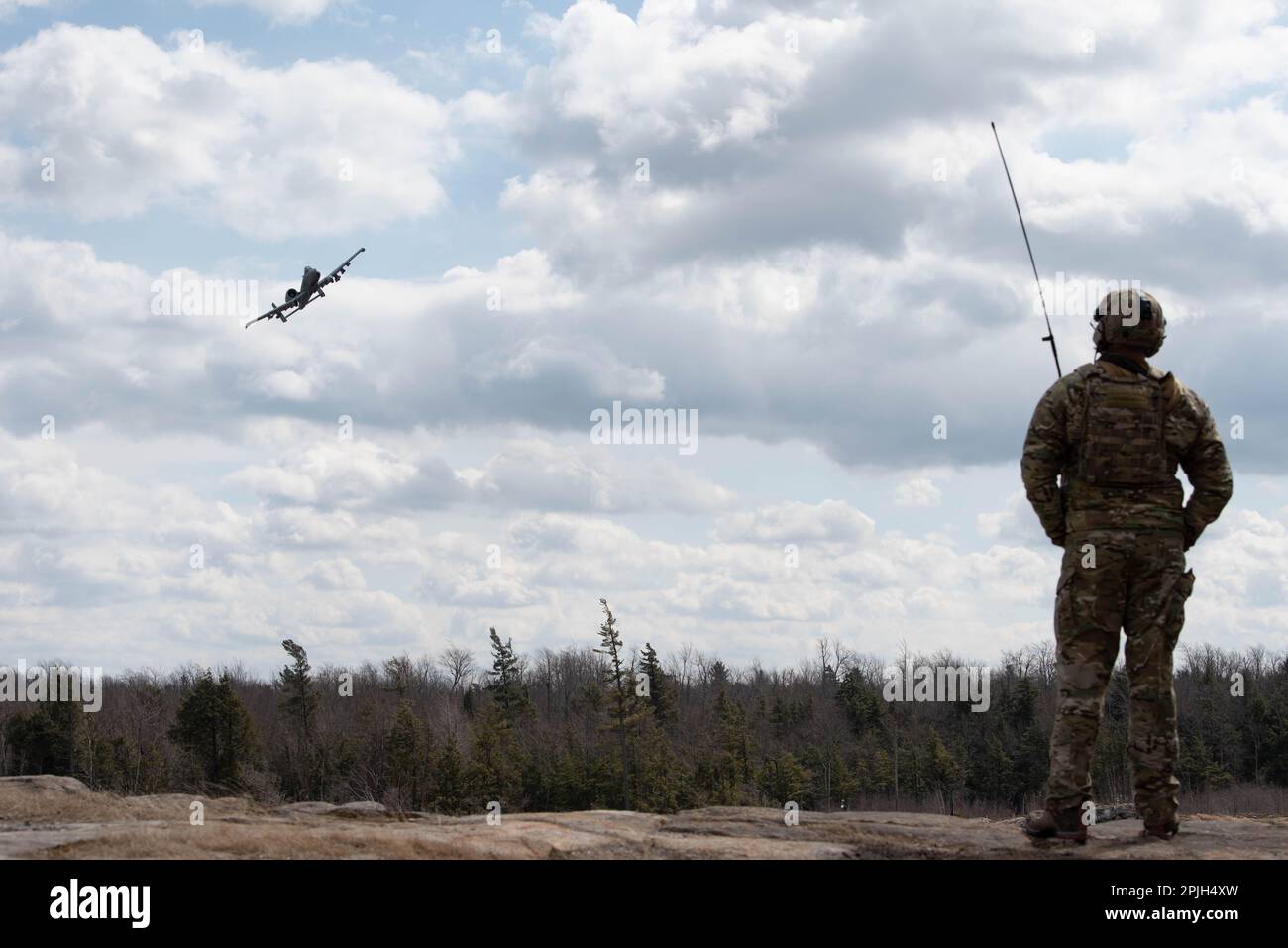 A Tactical Air Control Party (TACP) Airman assigned to the 274th Air Support Operations Squadron watches an A-10 Thunderbolt II from the 175th Wing, Baltimore, M.d., perform a show of force after a close air support exercise on Range 48, Fort Drum, N.y. March 29, 2023. The close air support training was conducted by members of the 274th ASOS and members of the Brazilian Air Force Para-SAR Squadron. Stock Photo