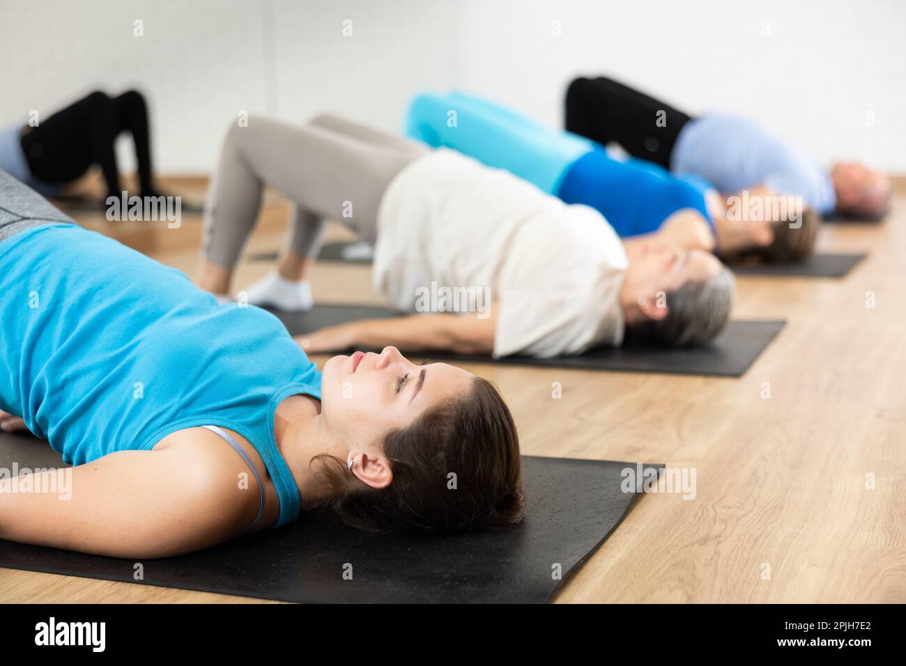 People of different ages performing glute bridge during group Pilates