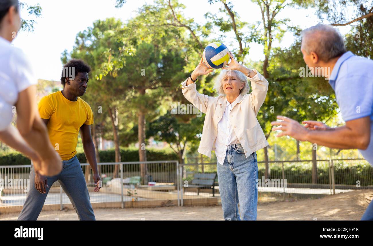 Positive multiracial friends of different ages throwing up a volleyball