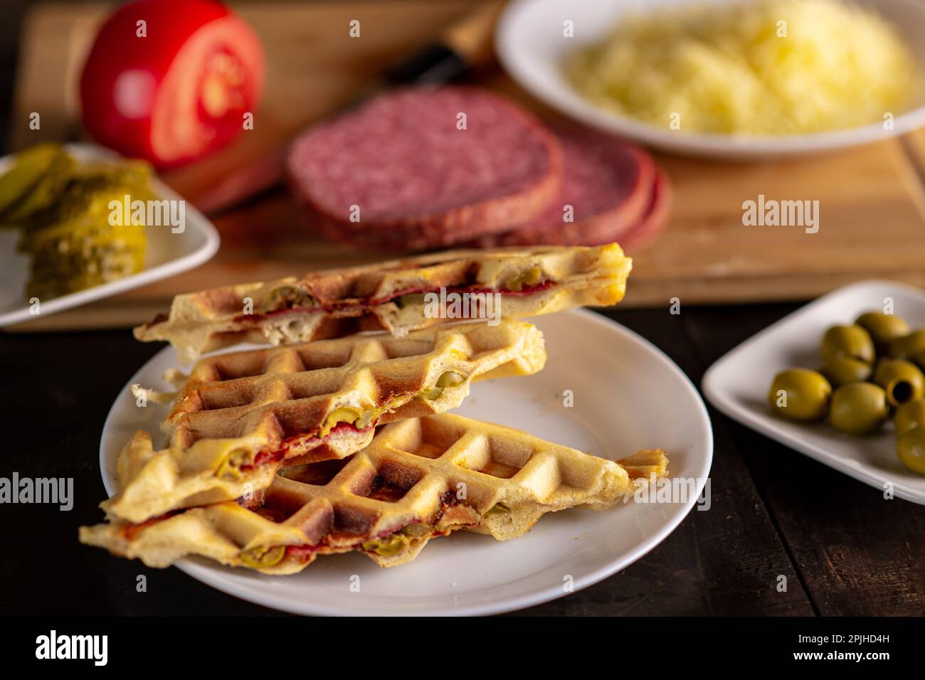 https://c8.alamy.com/comp/2PJHD4H/pizza-waffles-piffle-waffles-stuffed-with-sausage-cheese-tomatoes-on-a-plate-surrounded-by-cooking-ingredients-2PJHD4H.jpg