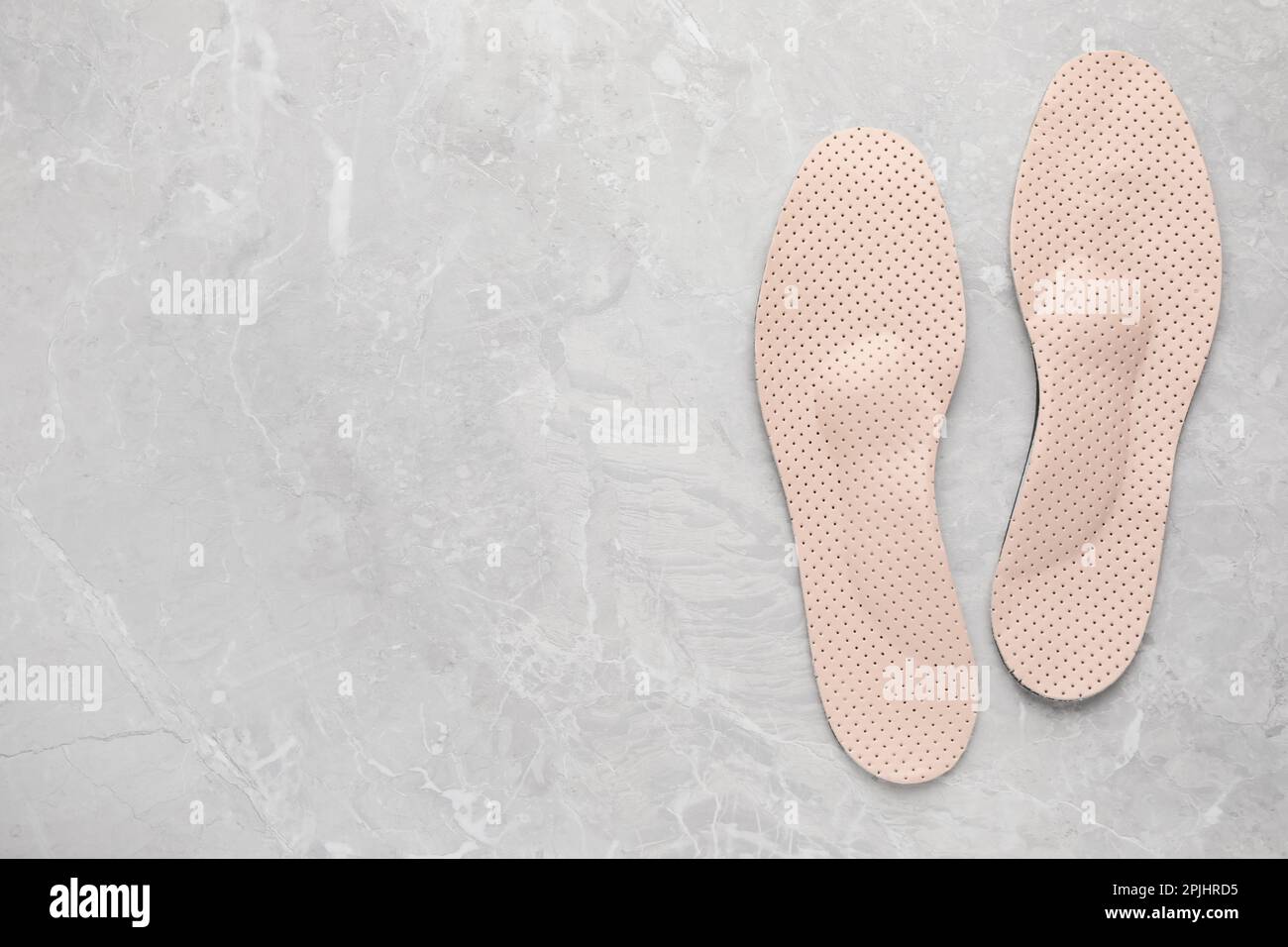 Beige orthopedic insoles on light grey marble background, flat lay ...