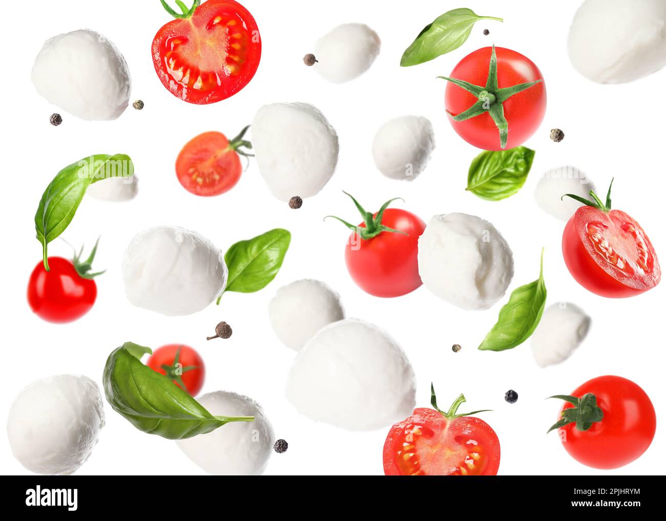 Mozzarella cheese balls, tomatoes, basil leaves and peppercorns for caprese salad flying on