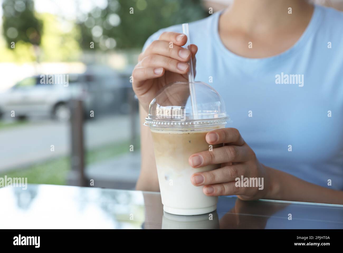 https://c8.alamy.com/comp/2PJHT0A/woman-with-plastic-takeaway-cup-of-delicious-iced-coffee-at-table-in-outdoor-cafe-closeup-2PJHT0A.jpg