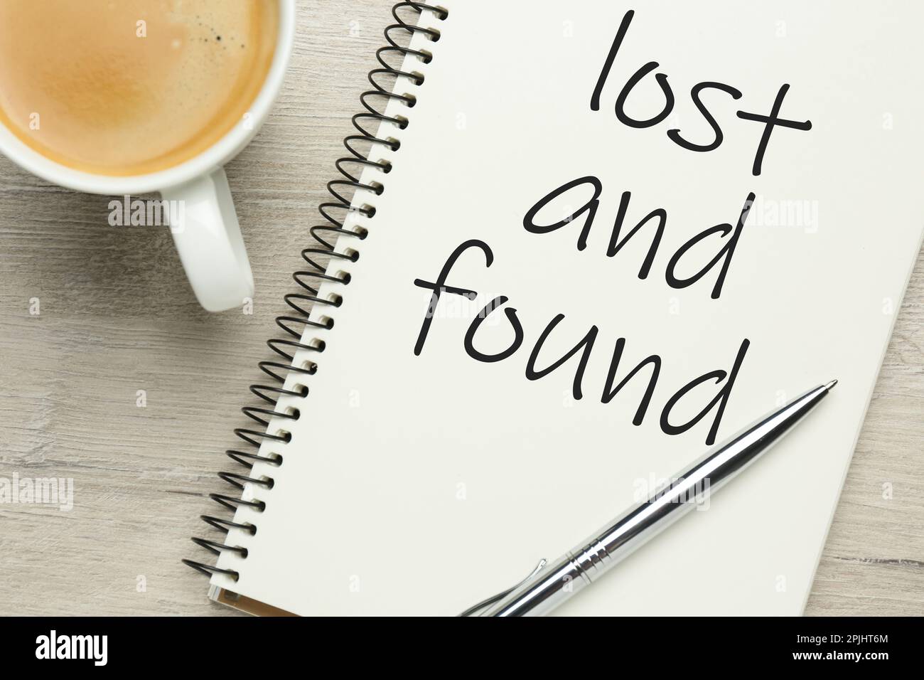 Notebook with phrase Lost and Found, cup of coffee and pen on white wooden table, flat lay Stock Photo