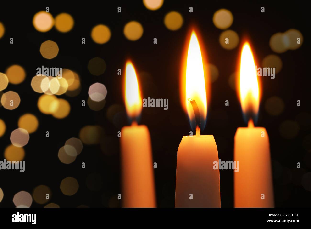 Burning candles on dark background with blurred lights, closeup. Bokeh ...