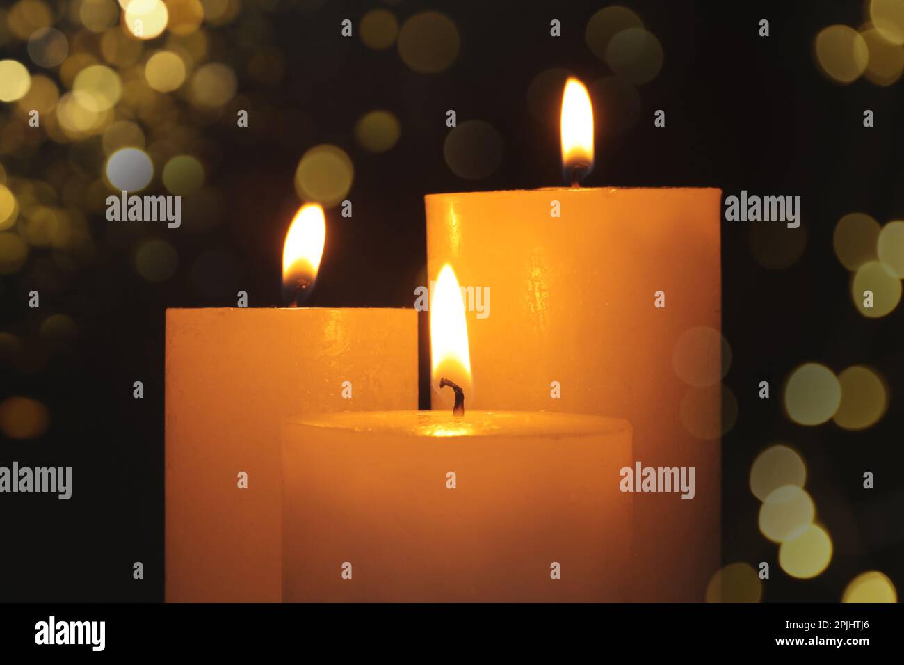 Burning candles on dark background with blurred lights, closeup. Bokeh ...