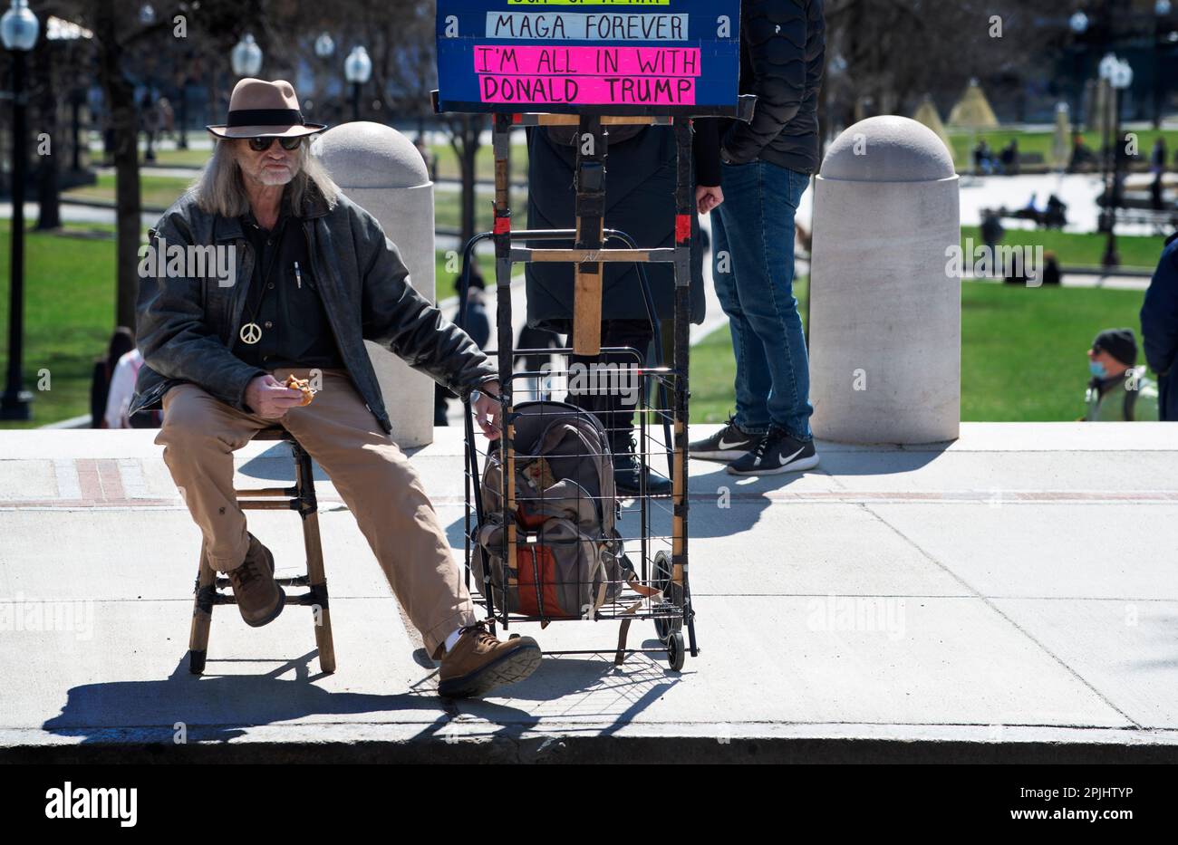 Trump Indictment: 31 March 2023, Boston, MA, USA: A single Trump supporter, Bob, 69, sat across Beacon Street in central Boston as small group of supporters of the prosecution of former U.S. President Donald Trump gathered on the steps of the Massachusetts State House in central Boston at noon on Friday. Stock Photo
