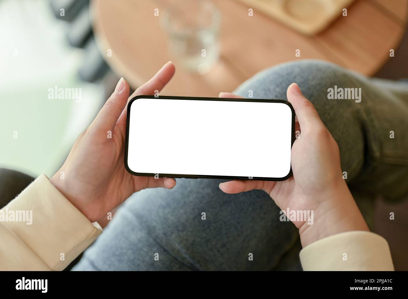 Top view of a female watching something on her phone, holding a smartphone in horizontal position. Stock Photo