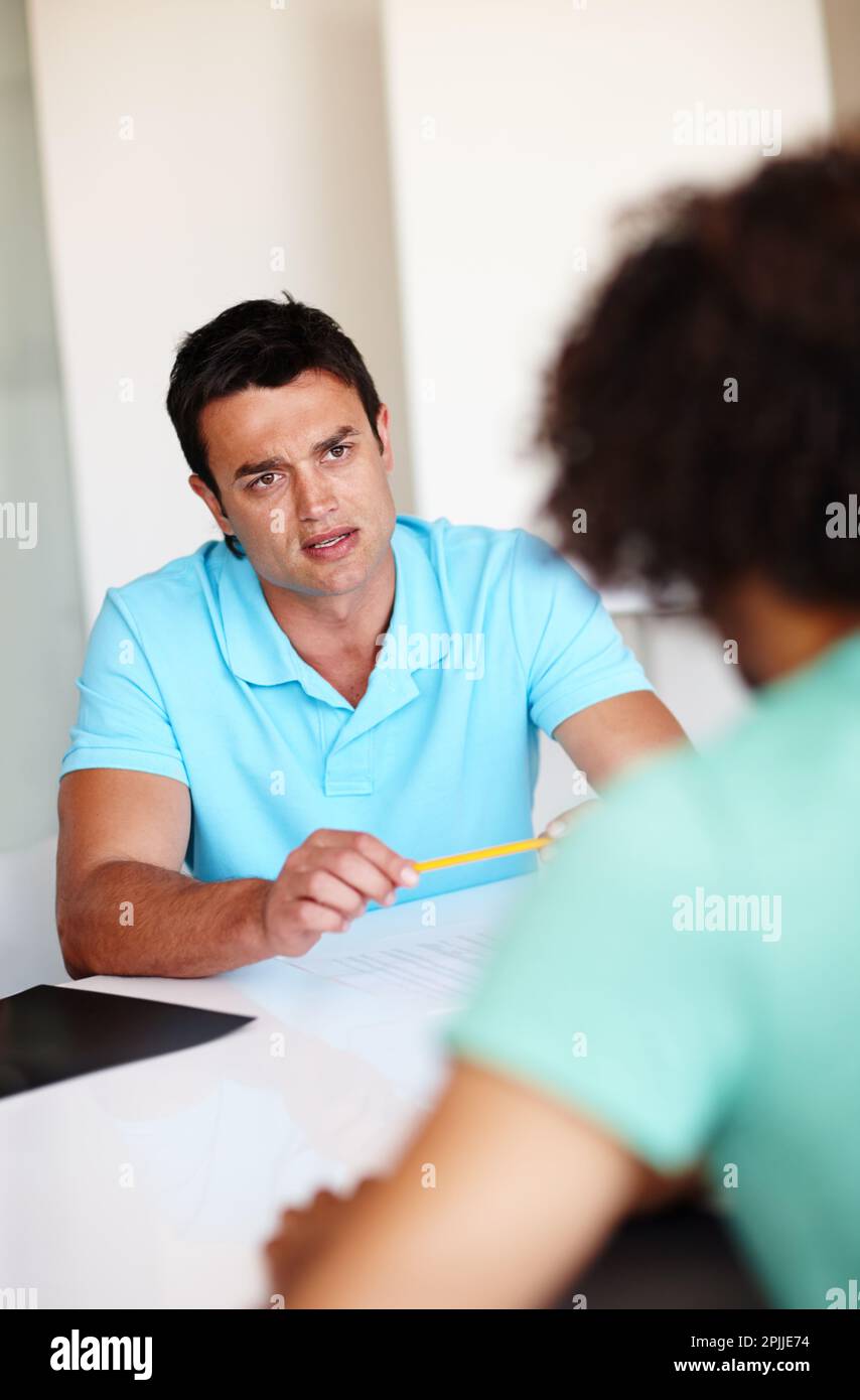 Sitting at the negotiations table. Young colleagues having a meeting in the office. Stock Photo