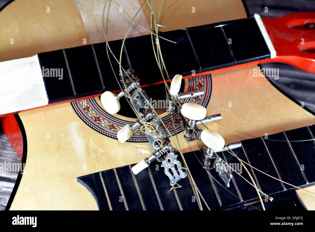 A broken wooden old classic guitar with damaged strings chords