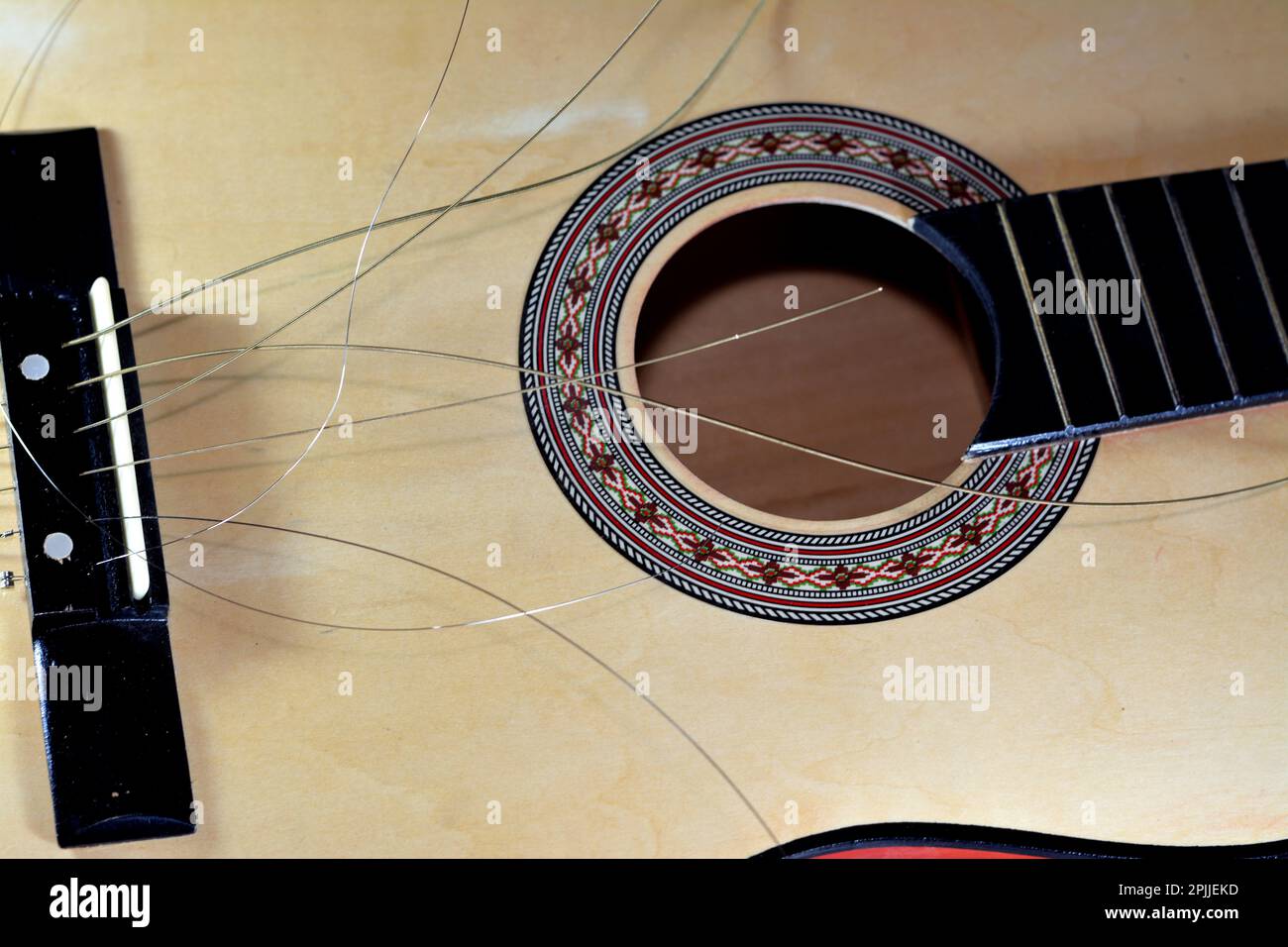 A broken wooden old classic guitar with damaged strings chords