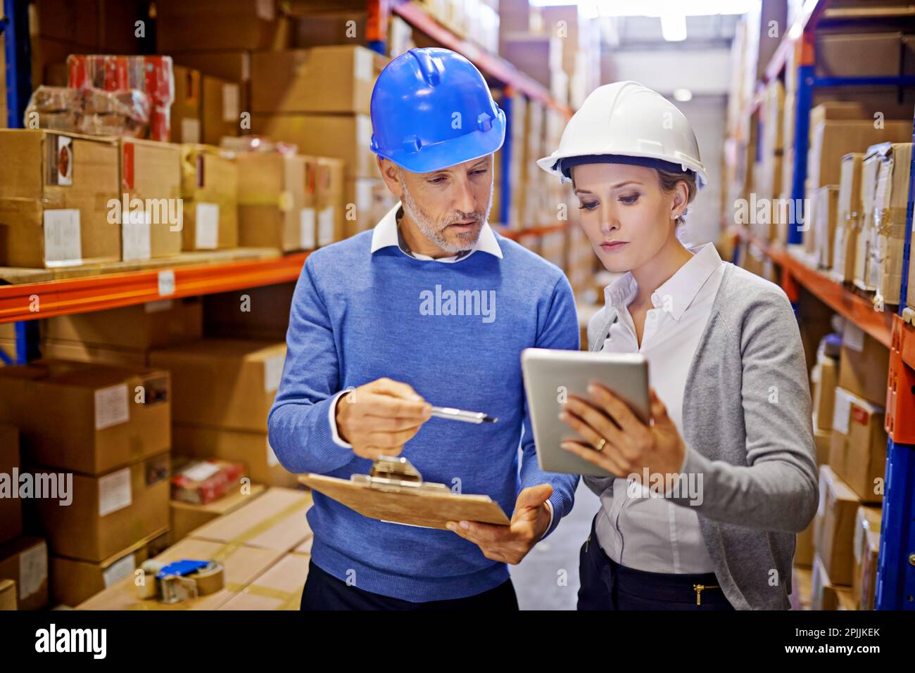 Someone Inspecting Inventory Comparing order stats. a man and woman inspecting inventory in a large ...