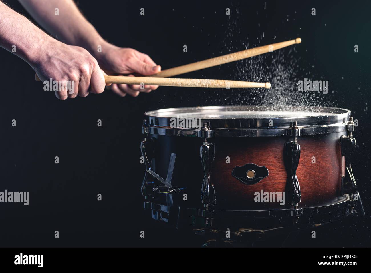 Drummer using drum sticks hitting snare drum with splashing water Stock