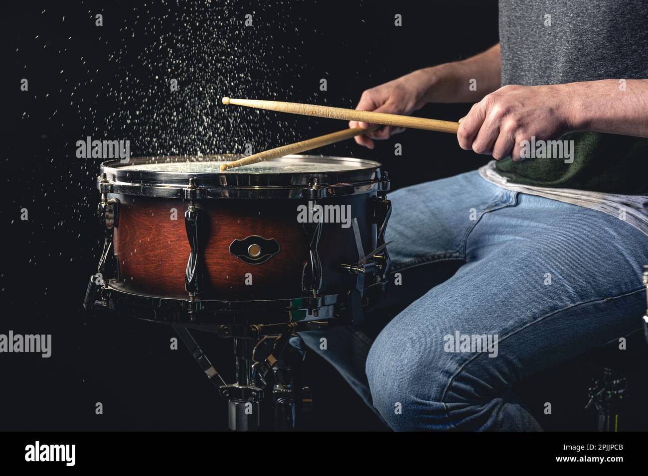 Drummer using drum sticks hitting snare drum with splashing water Stock