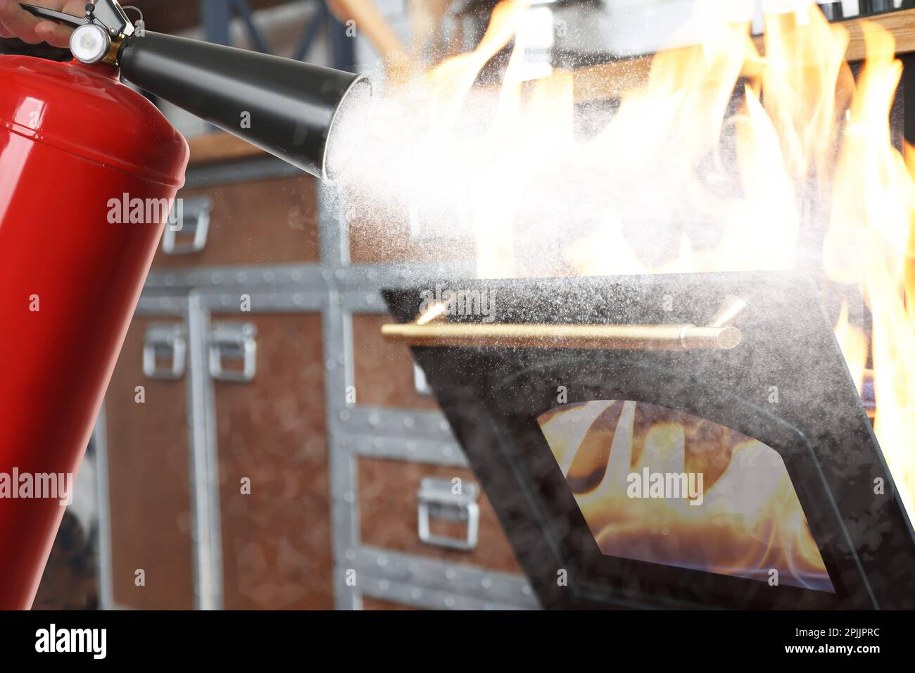 Putting out burning oven with fire extinguisher in kitchen Stock Photo