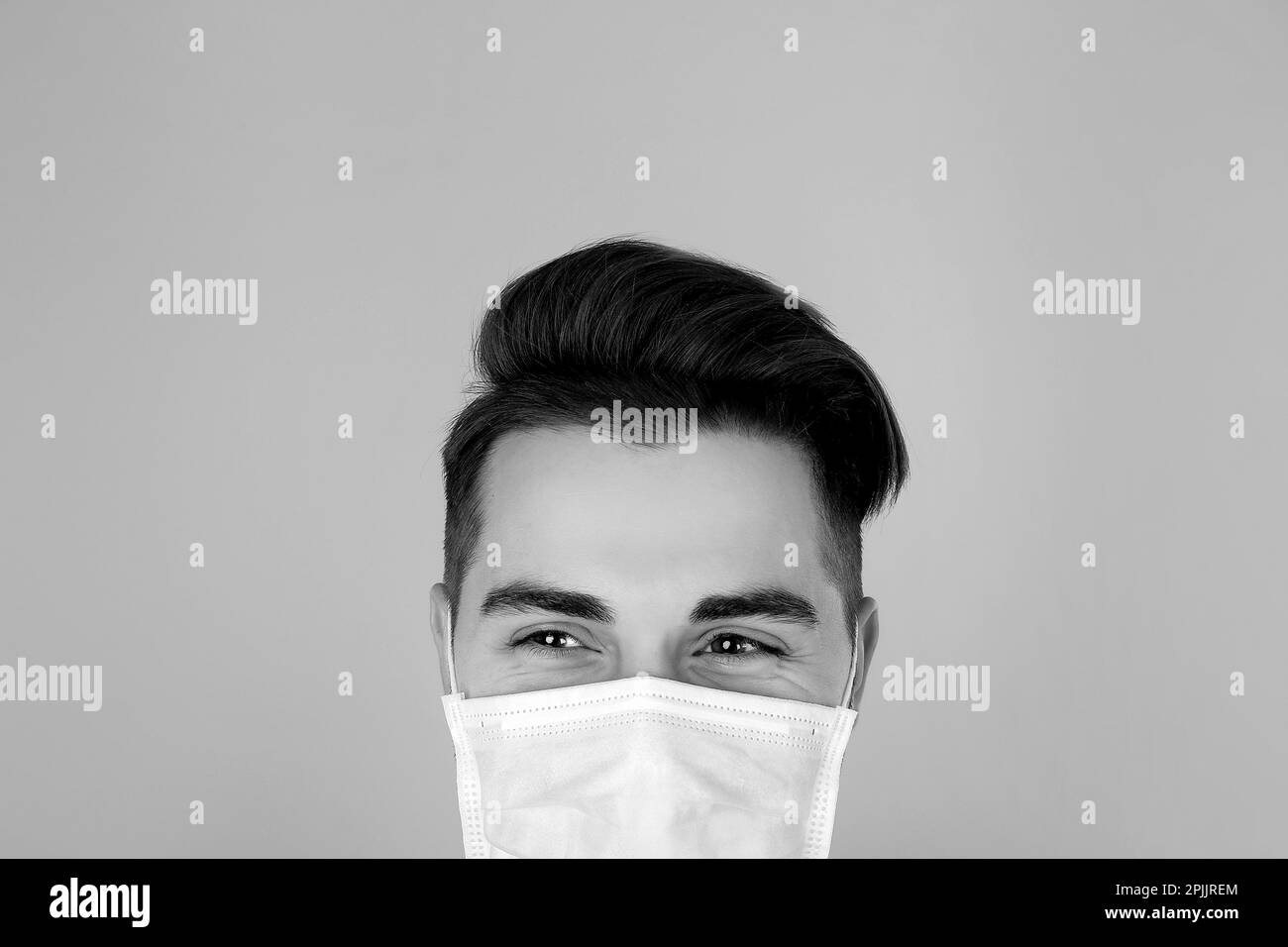 Man wearing medical face mask on light background. Black and white photography Stock Photo