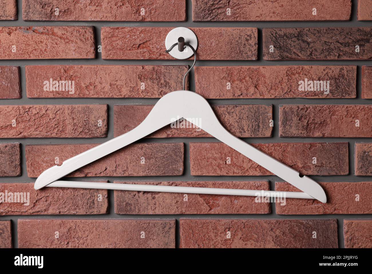 White clothes hanger on red brick wall Stock Photo