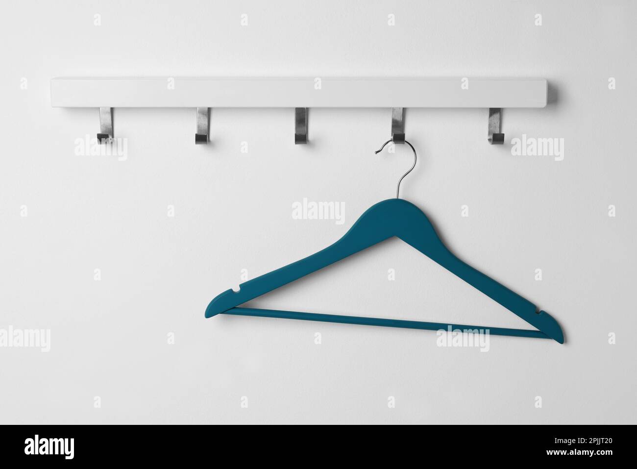 Rack with empty blue clothes hanger on white wall Stock Photo Alamy
