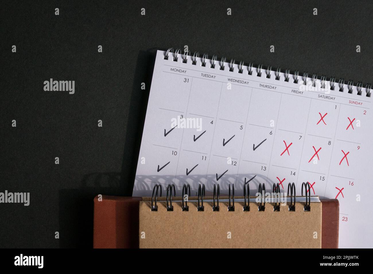 Calendar with ticks and crosses, depicting four day work week concept. Top view. Copy space. Stock Photo