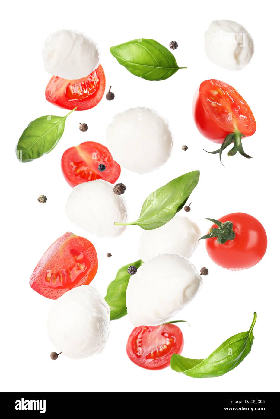Mozzarella cheese balls, tomatoes, basil leaves and peppercorns for caprese salad flying on
