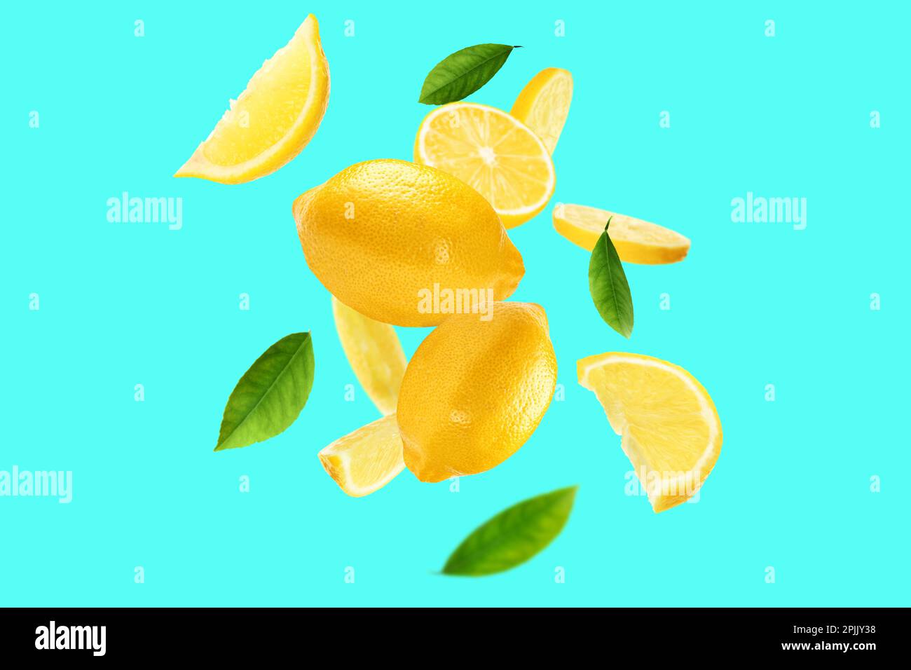 Fresh ripe lemons and green leaves flying on cyan background Stock Photo