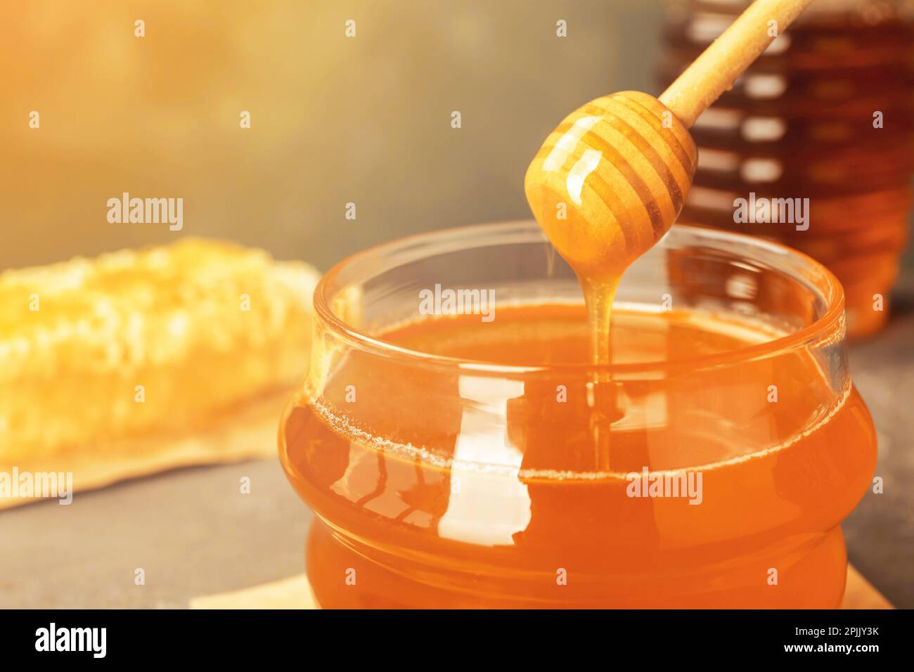 Sweet honey dripping from dipper into glass jar, closeup Stock Photo ...