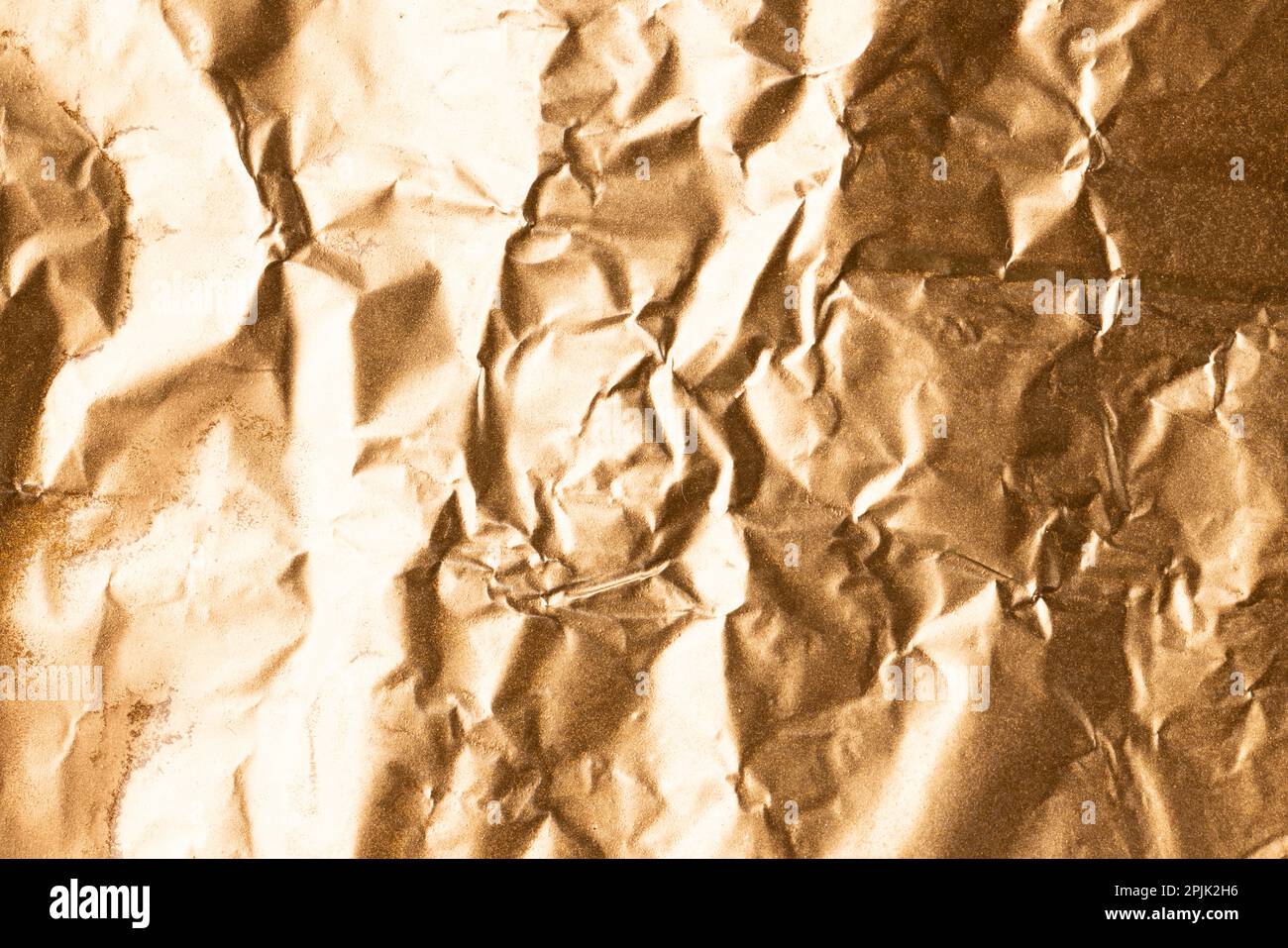 Close up of crumpled and shiny gold foil with copy space Stock Photo