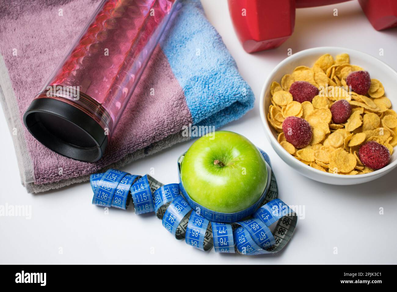 Healthy food, weight loss and diet concept, green apple, measuring tape, dumbbell, towel, cereal and bottle of water  on a white background. Stock Photo
