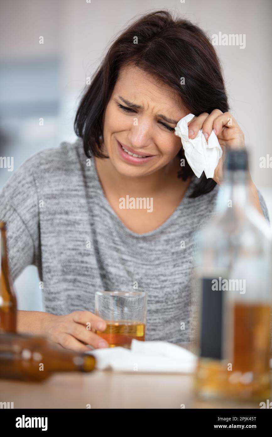 young depressed woman sinking in alcohol Stock Photo