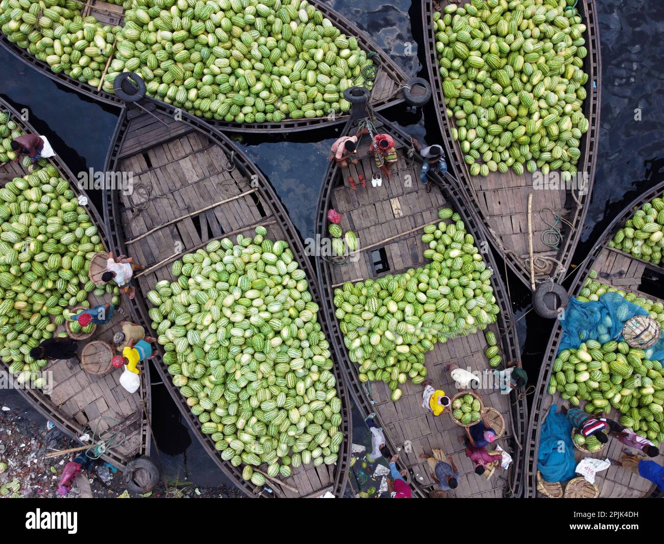 Dhaka, Dhaka, Bangladesh. 3rd Apr, 2023. Dozens of boats, carrying thousands of bright green watermelons, dock at a bustling market near the Buriganga River in Dhaka, Bangladesh. Traders bring the fruits from rural agricultural river areas to the country's capital Dhaka for distribution across the country. The workers, who earn just 3.50 GBP per day, spend all day unloading heavy baskets of watermelons. Each watermelon is sold for less than 1 GBP. Full of health benefits, watermelons are now turning out to be a preferred ingredient for restaurants, and five-star hotels, and are used in salads Stock Photo