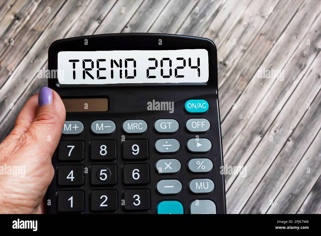 Trend 2024 text message on calculator display in female hand on wooden background Stock Photo