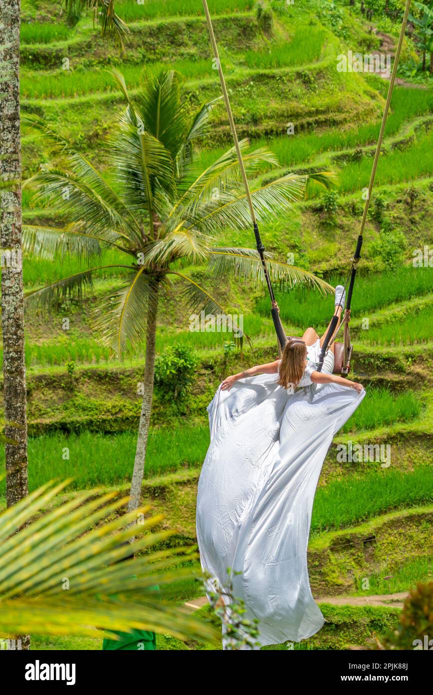 Tegalalang, Ubud, Indonasia - February 14.2023 :A woman in white long dress  on a swing at the natural terrace swing fairground rice fields on Bali  Stock Photo - Alamy