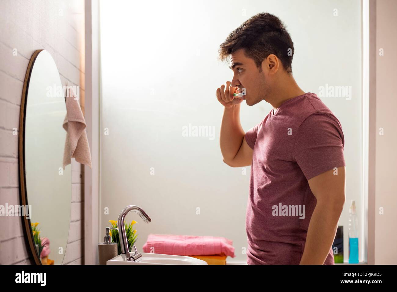 Young man brushing his teeth in bathroom Stock Photo