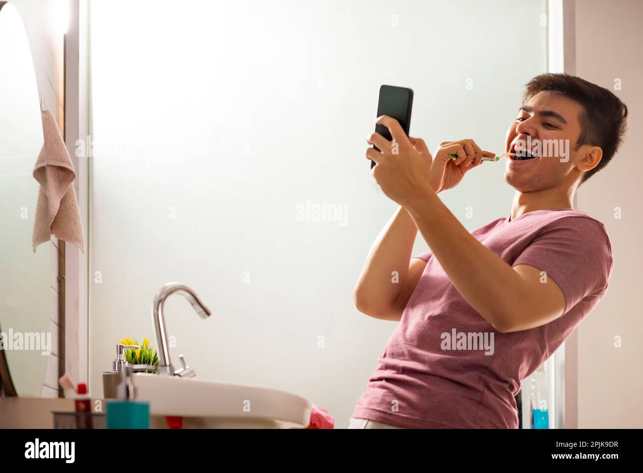 Young man having video call  while brushing teeth in bathroom Stock Photo