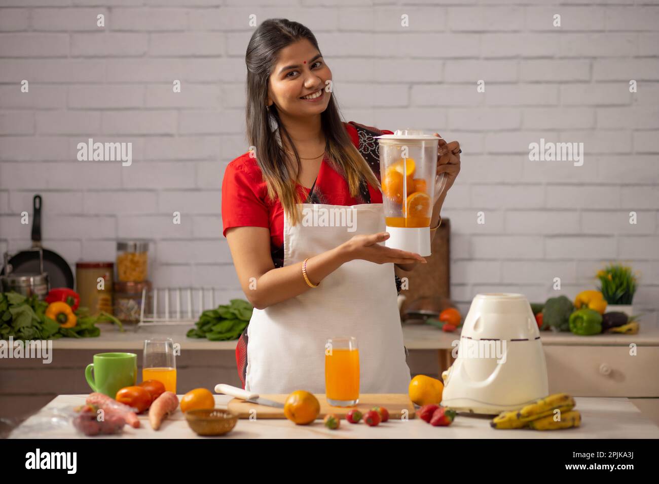 Smiling woman making orange juice in kitchen Stock Photo