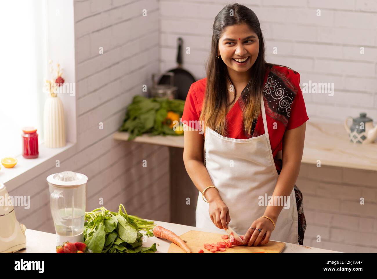Smiling woman chopping vegetables in kitchen Stock Photo