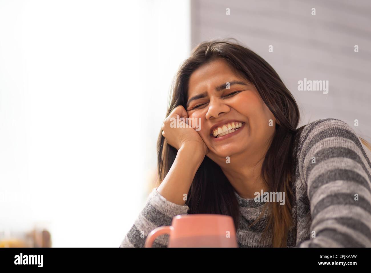 Close-up portrait of smiling woman drinking coffee at home Stock Photo