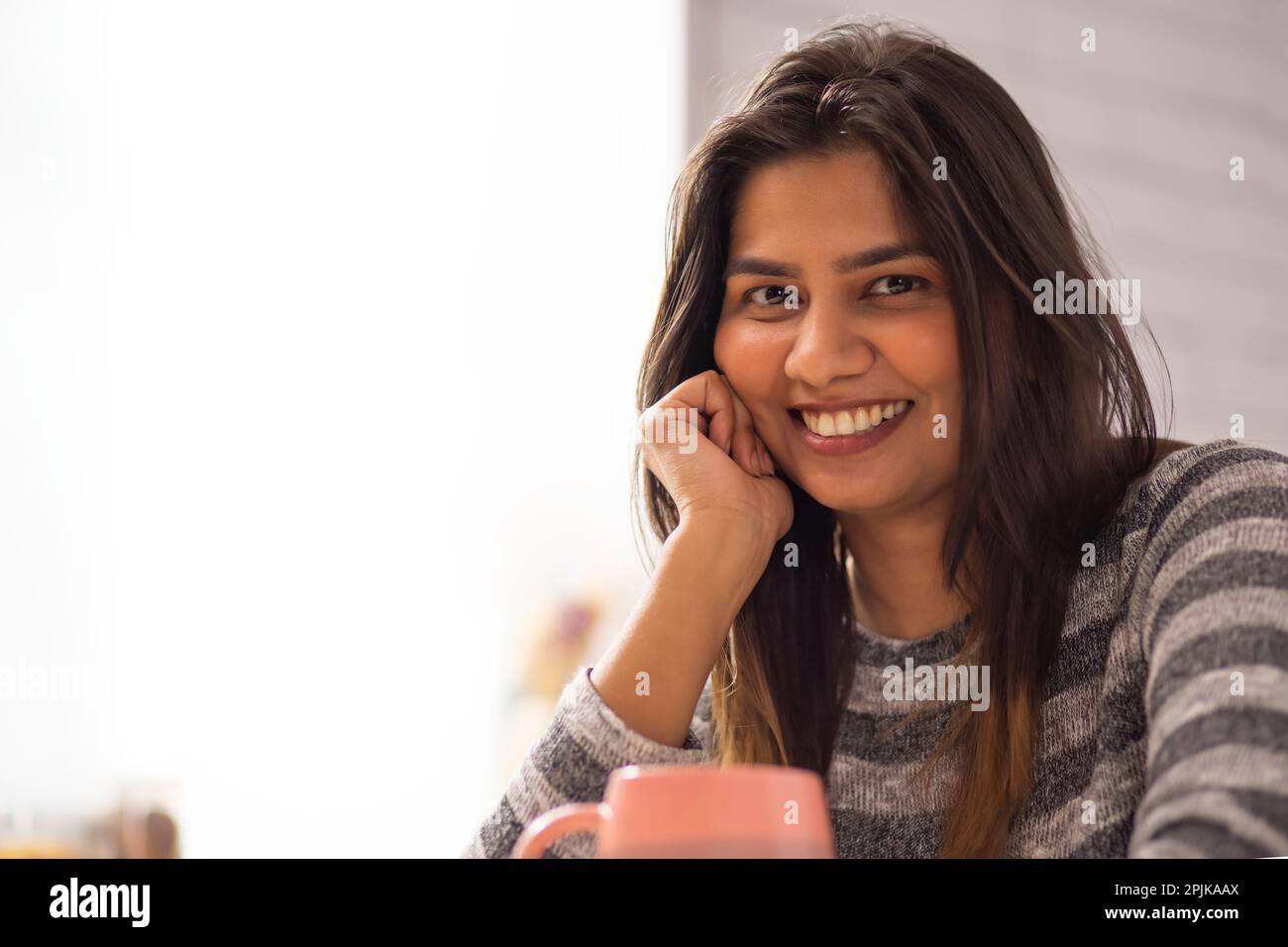 Close-up portrait of smiling woman drinking coffee at home Stock Photo