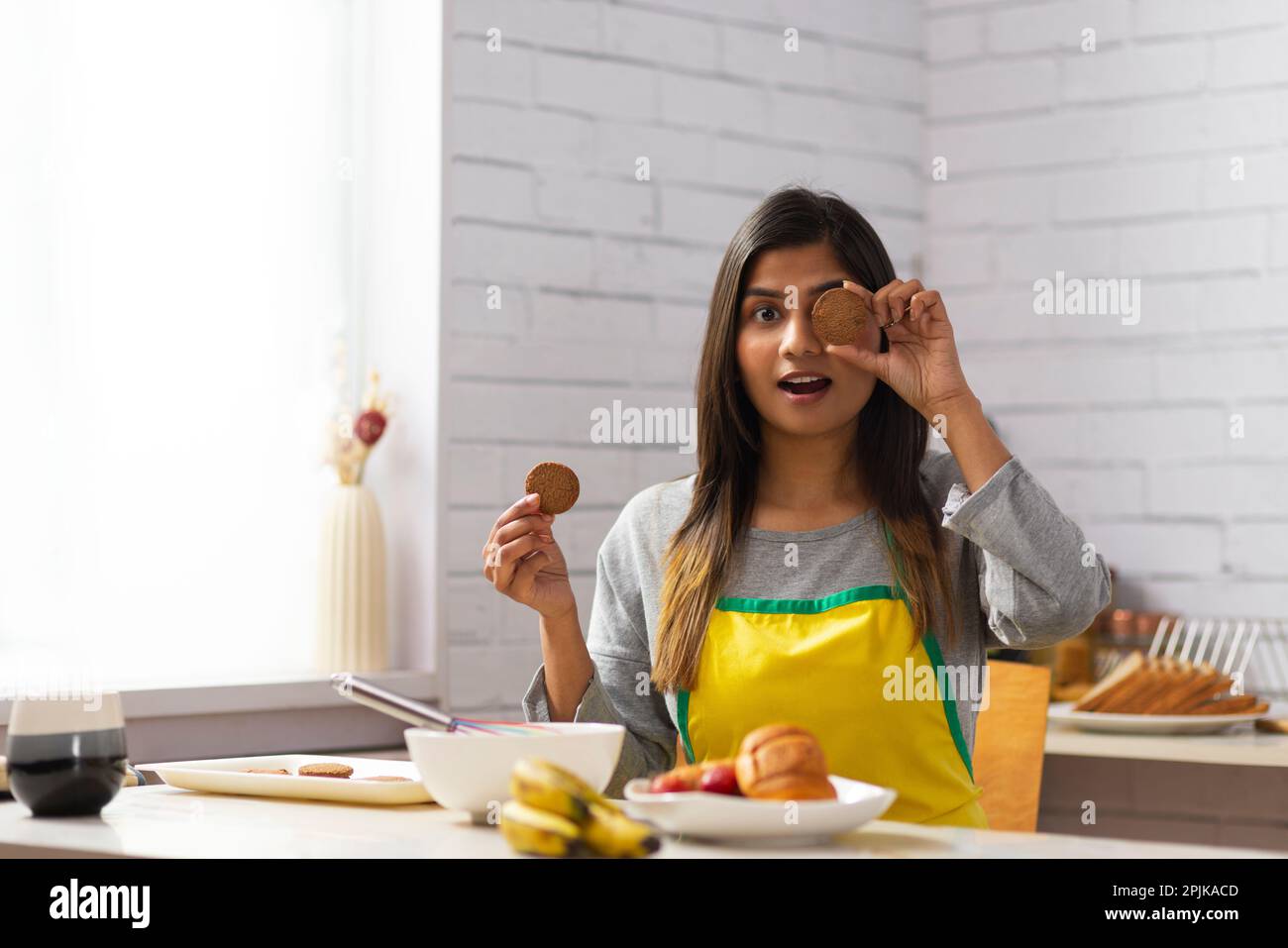 Woman enjoying her breakfast with cookies in kitchen Stock Photo