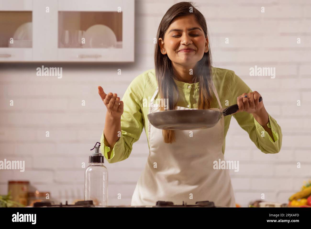 Woman smelling food while cooking in kitchen Stock Photo Alamy