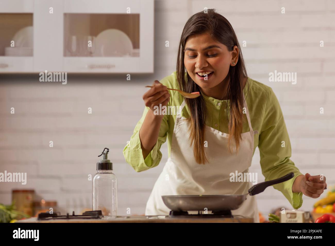 Portrait of cheerful woman cooking in kitchen Stock Photo
