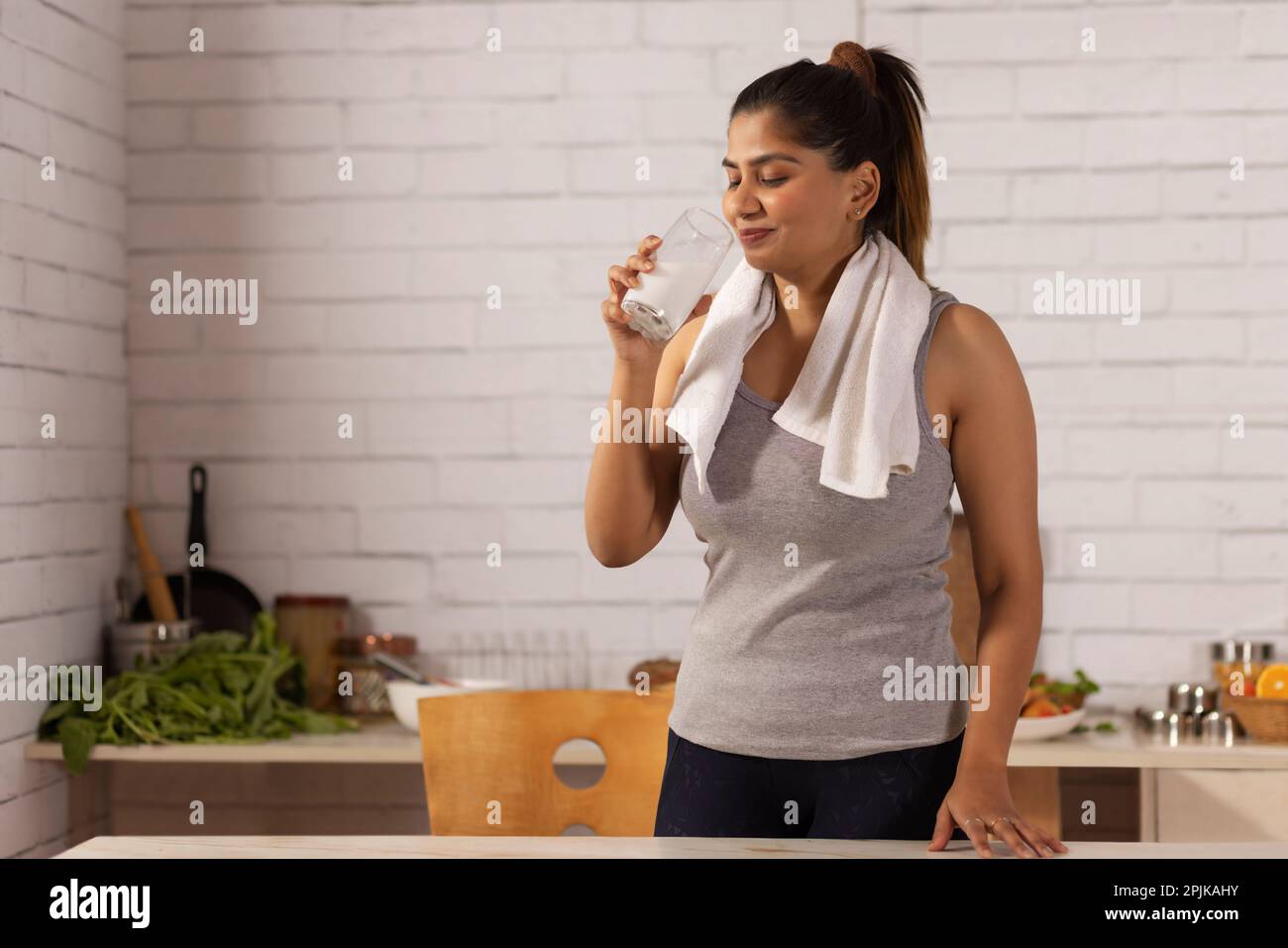 Cheerful woman drinking milk in kitchen Stock Photo