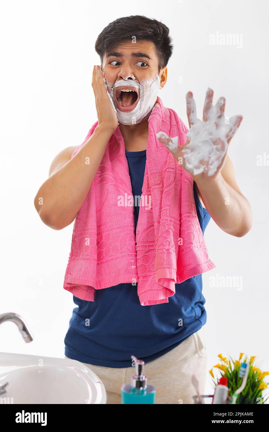Portrait of scared young man screaming while shaving Stock Photo