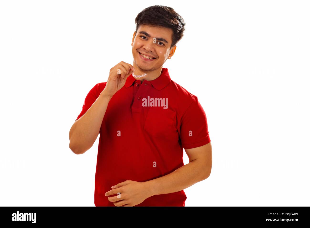 Smiling young man holding teeth aligner against white background Stock ...