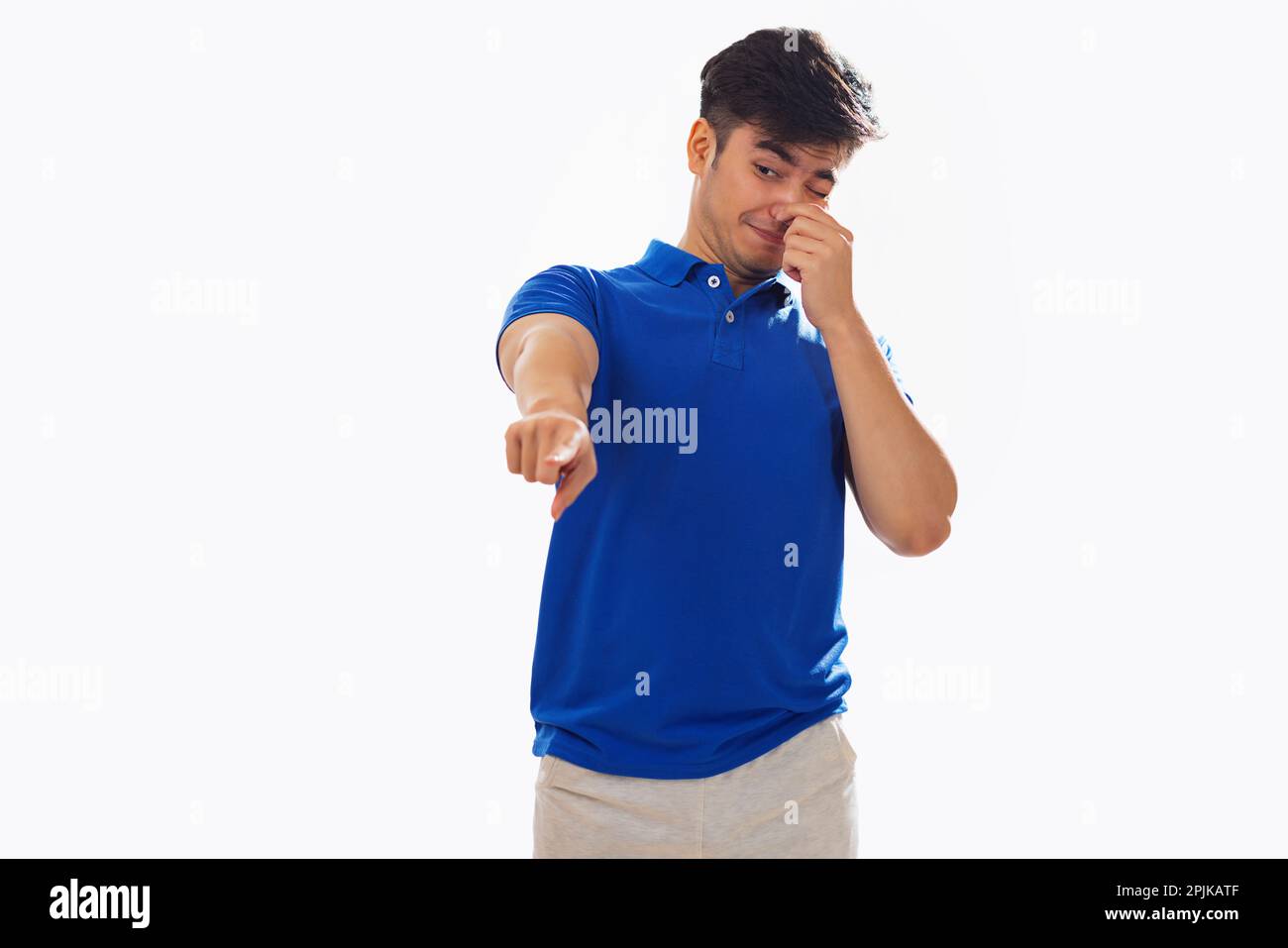 Young man covering his nose due to bad smell against white background Stock Photo