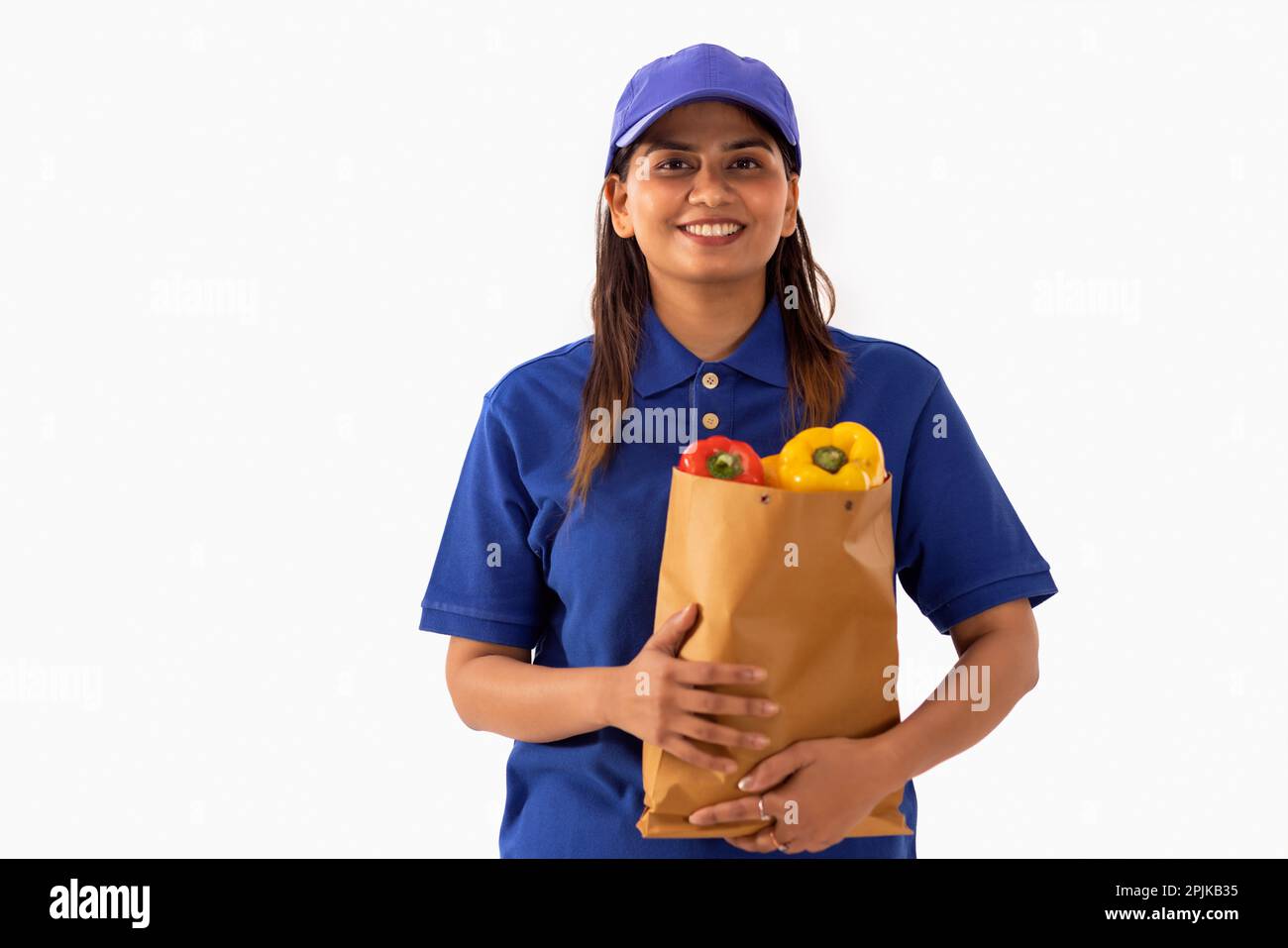 Portrait of delivery woman holding a bag of fresh vegetable against white background Stock Photo