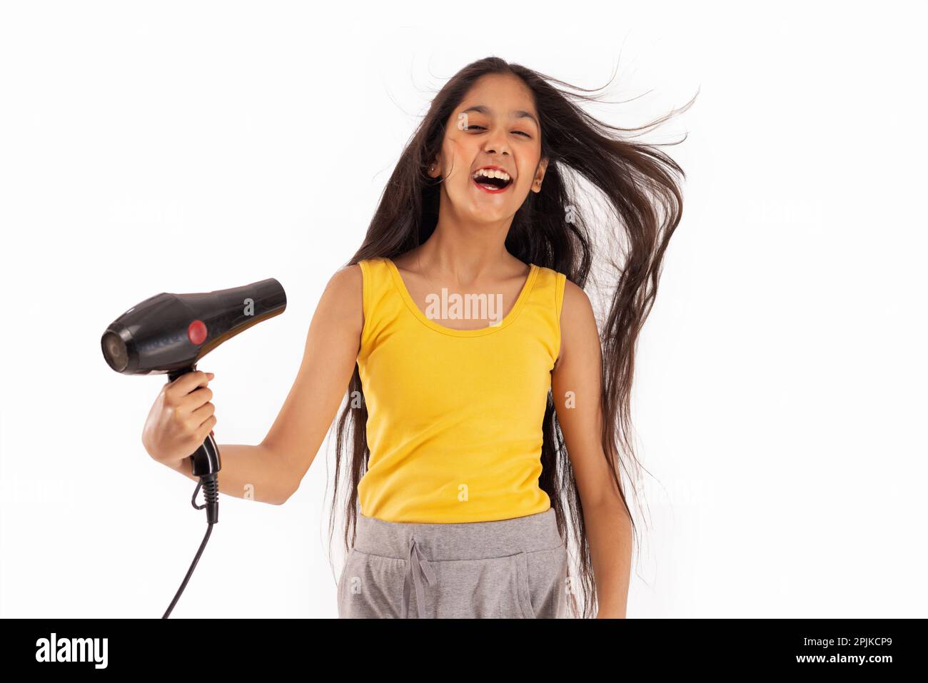 Tween girl drying her hair against white background Stock Photo
